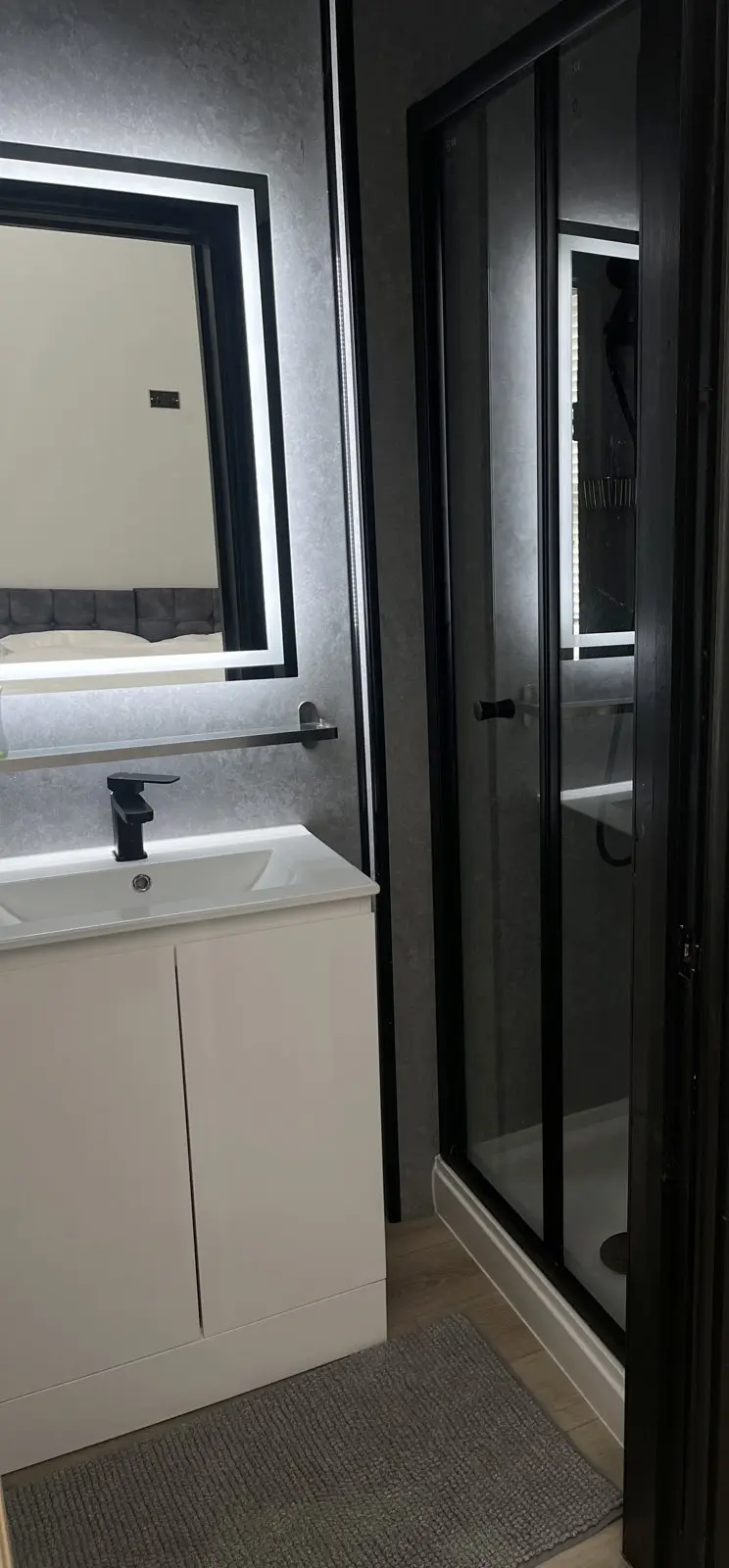 Ensuite with black-framed shower and illuminated mirror