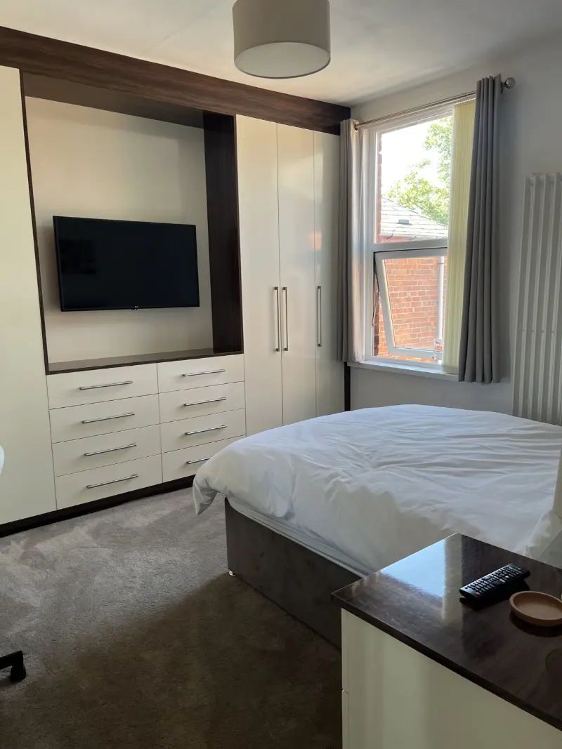A bright, freshly made bedroom with fitted wardrobes