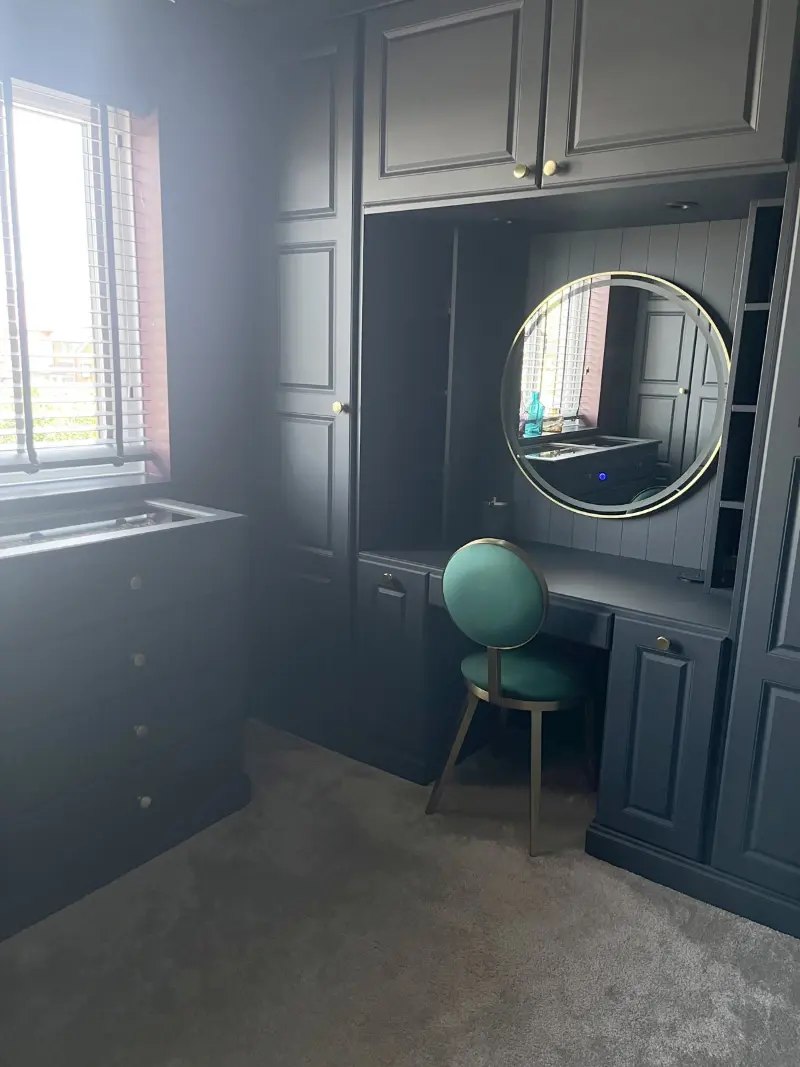 Navy fitted dressing room with round mirror and green velvet chair