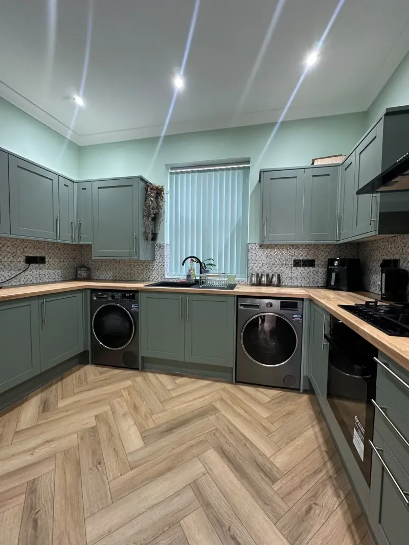 Sage green kitchen with oak worktops and herringbone floor