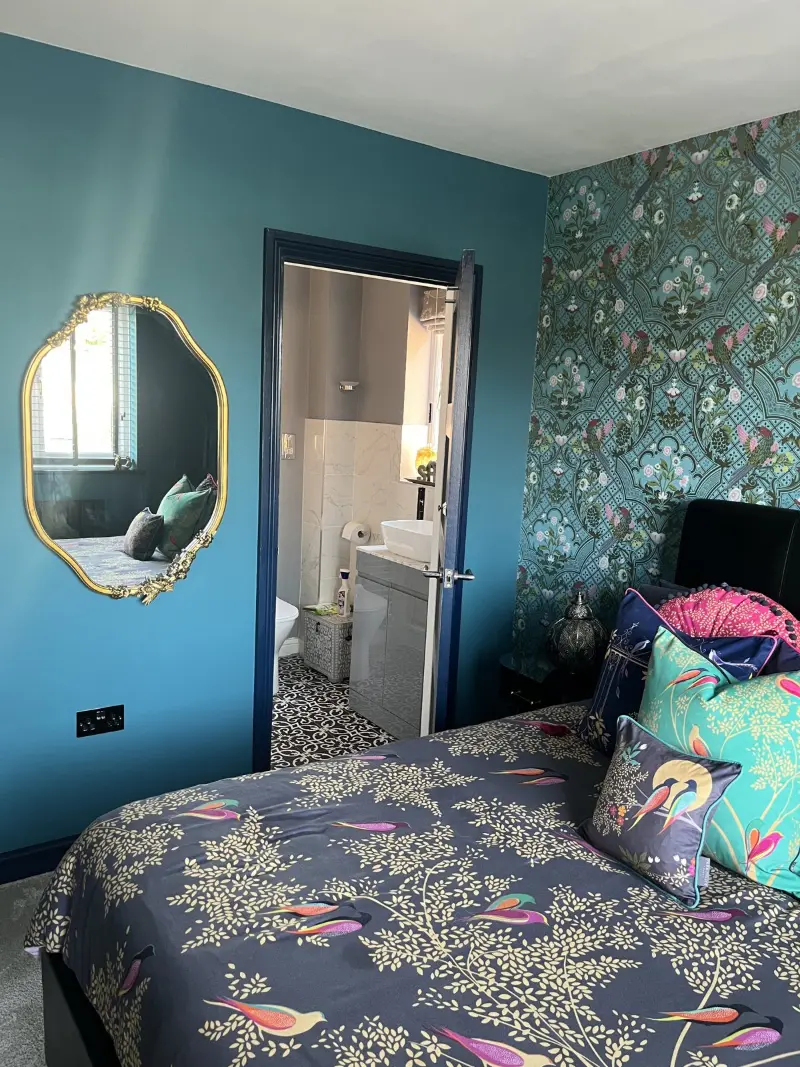 Teal bedroom with patterned wallpaper and gold mirror, cleaned by Blanc Cleaning