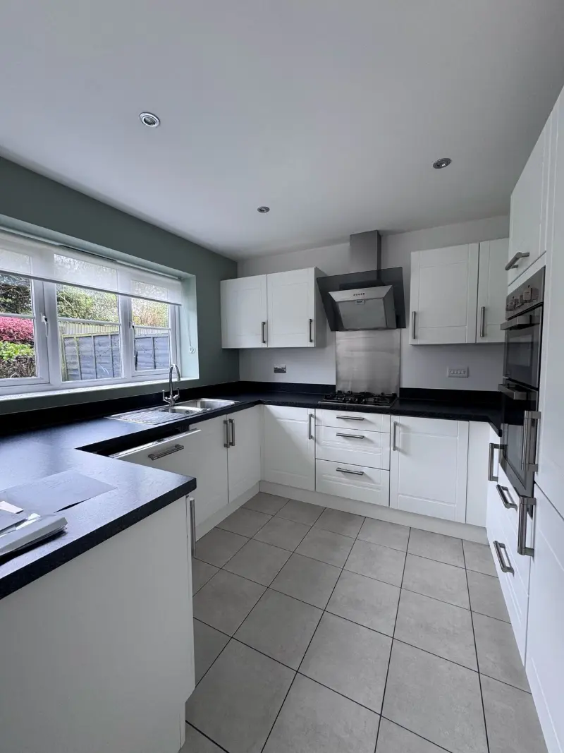 White kitchen with black worktops and tiled floor